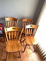 Set of four honey oak spindle back chairs grouped together