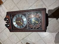 Full view of wall clock showing wooden case, dial, fretwork panel and pendulum