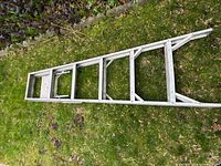 Ladder folded lying on grass, showing full length and side