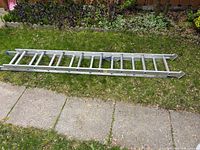 Full view of aluminum extension ladder retracted on grass