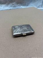Closed silver cigarette case showing exterior Art Nouveau floral design
