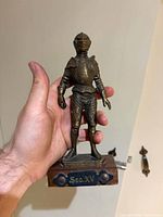 Front view of bronze-plated knight figurine on wood base