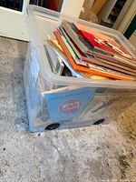 Plastic tote filled with stacked children's books, visible Seedling Publications title at front