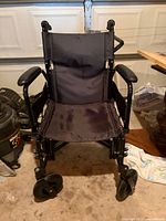 Front view of wheelchair showing seat, casters, frame