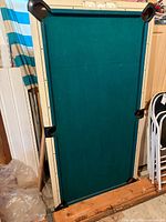 Front of folded pool table showing green felt and corners