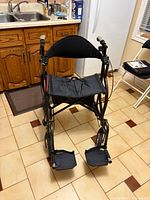 Full front view of black Fusion rollator showing seat, backrest, footrests and all four wheels