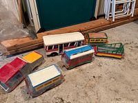 Group view of six hand-painted wooden vehicles on floor