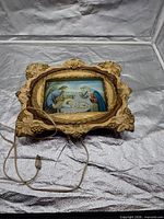 Front view of plaque showing nativity image and ornate frame with power cord