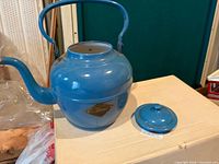 Full view of blue enamel kettle with lid beside it