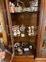 Overview of cabinet shelves showing crystal, figurines and silverplate pieces