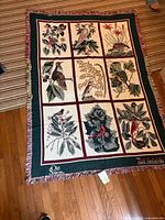 Full view of throw blanket showing bird and botanical nine-panel design, border, fringe, Old Salem logo