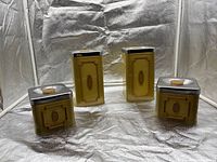 Front view of four olive canisters with lids