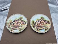 Both ESD Japan hand-painted cottage scene plates side by side