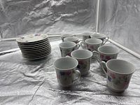 Stack of 12 saucers beside 11 cups in light tent