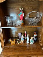 Bottom shelf with assorted porcelain figurines, gold-tone cherubs, ship model and ceramic gondola