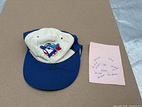 Cap front with Blue Jays logo, signatures, and pink list