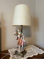 Full view of lamp with shade showing porcelain figures and metal base