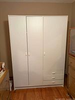 Full front view of closed white 3-door wardrobe