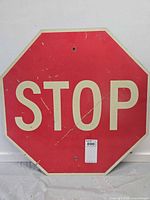 Front of red octagonal stop sign showing lettering and wear