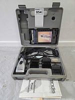 Open carrying case showing clipper, combs, VHS tape and manual