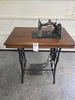 Full view of treadle sewing machine on wood table with iron base