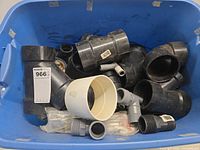 Blue bin of assorted black ABS and gray PVC fittings