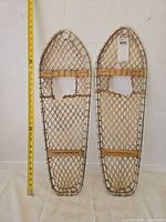Full view of both snowshoes with measuring tape for length reference