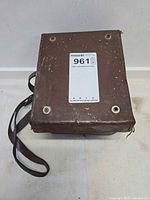 Closed brown carrying case with strap, showing overall wear