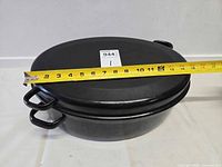 Closed oval roasting pan with lid, tape measure showing length