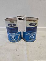 Front view of both Ford 1 L power steering fluid cans showing labels and surface wear