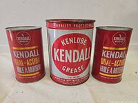 Front view of three Kendall cans—two quart oil cans flanking 5-lb grease can.