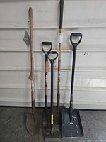 Full view of five long-handled tools against wall