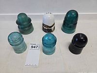 Group shot of six insulators—five glass, one porcelain—showing colors and overall form