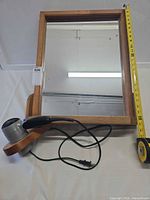 Front view of mirror showing full frame, attached holder, hair dryer, height tape