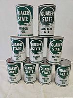 Front view of nine stacked Quaker State quart cans showing logos and condition