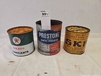 Front view of the three vintage cans displaying brand logos and condition