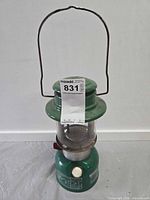 Full view of green Coleman lantern with bail handle upright