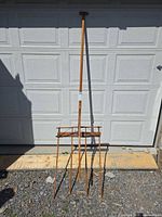 Full view of the wooden hay rake leaning against garage door