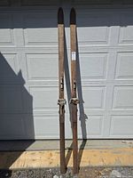Full view of both wooden skis standing upright in front of garage door