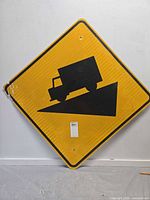 Full view of diamond yellow sign with truck decline graphic, showing bent corner and mounting holes