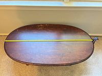 Top view showing full oval table and measuring tape across length