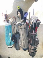 Three golf bags with mixed clubs and headcovers hanging