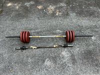 Overall view of straight barbell loaded with four plates and EZ curl bar beneath