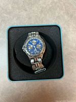 Watch in presentation tin showing blue dial and bracelet