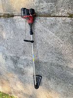Full view of string trimmer showing entire length, engine housing, shaft and guard