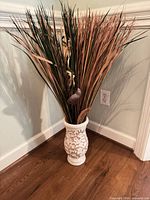 Full view of vase with faux grass placed on floor