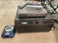 Overall lot showing DVD player, VideoNow handheld, GameStuff box, remote, IR receiver, cables