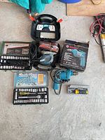Overview showing drill, sander in case, socket sets, bit set and cords