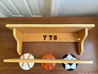 Top view of wooden wall shelf showing sports ball hooks and bracket design