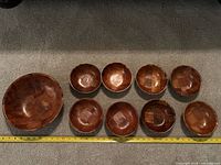 All ten wooden bowls arranged with measuring tape for scale